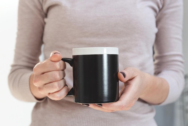 Mockup di tazza da caffè nero per dimostrazione di design tazza elegante mock up in mani femminili