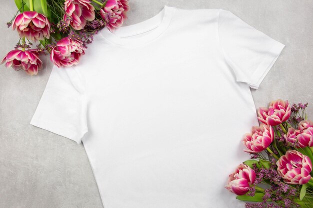 Mockup di tshirt in cotone bianco da donna con fiori di tulipani rosa su sfondo di cemento grigio Design modello di t-shirt stampa presentazione mock up vista dall'alto flat lay