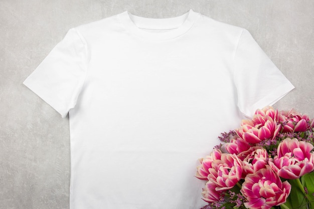 Mockup di tshirt in cotone bianco da donna con fiori di tulipani rosa su sfondo di cemento grigio Design modello di t-shirt stampa presentazione mock up vista dall'alto flat lay