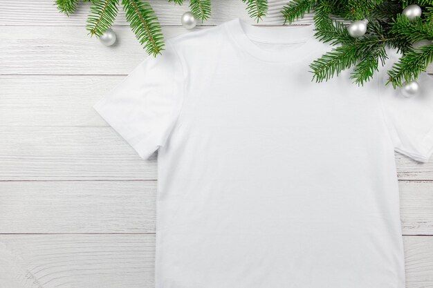 Mockup di tshirt in cotone bianco da donna con rami di albero di natale e decorazioni Design modello di t-shirt stampa presentazione flat lay mock up