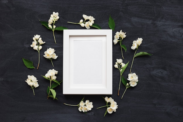 Mockup di vista dall'alto piatto di una cornice su uno sfondo nero con fiori selvatici. Bella foto di layout alla moda.