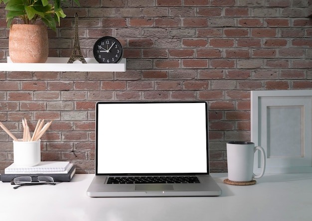 Mockup laptop con pianta d'appartamento tazza di caffè schermo vuoto e forniture su tavolo bianco