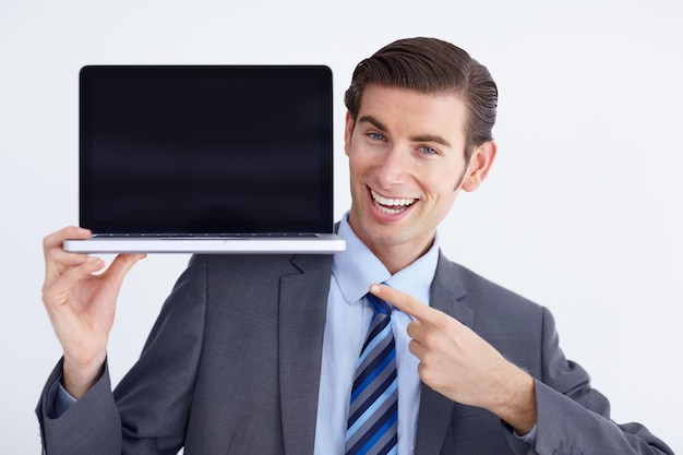 Mockup laptop e ritratto di uomo d'affari che punta allo spazio dello schermo su uno sfondo bianco Display delle mani e volto di persona di sesso maschile con spazio di copia del computer per il marketing pubblicitario o il branding