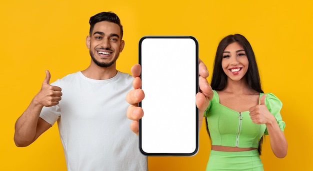 Mockup mobile Coppia mediorientale che dimostra smartphone vuoto e mostra i pollici in su