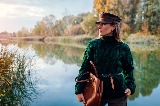 Moda autunno. Giovane donna che indossa attrezzatura alla moda e che tiene borsa all'aperto