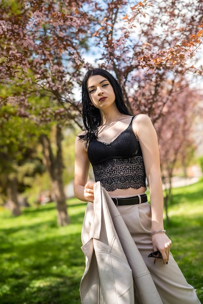 Moda bella ragazza in posa vicino a rami di alberi in fiore in primavera