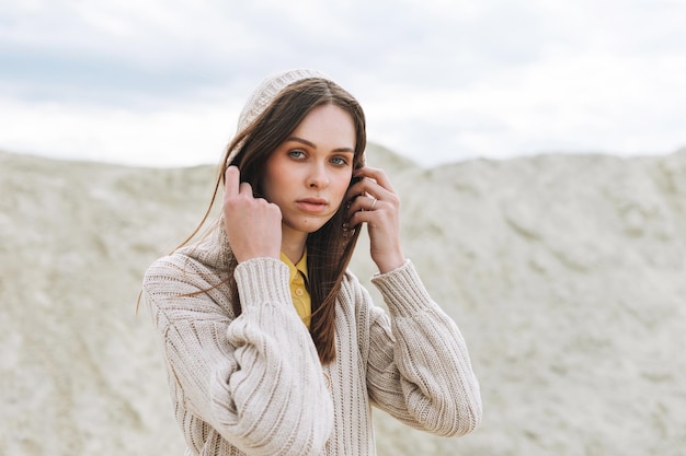 Moda bellezza ritratto di giovane donna con i capelli lunghi in cardigan lavorato a maglia su sfondo deserto vestito autunnale