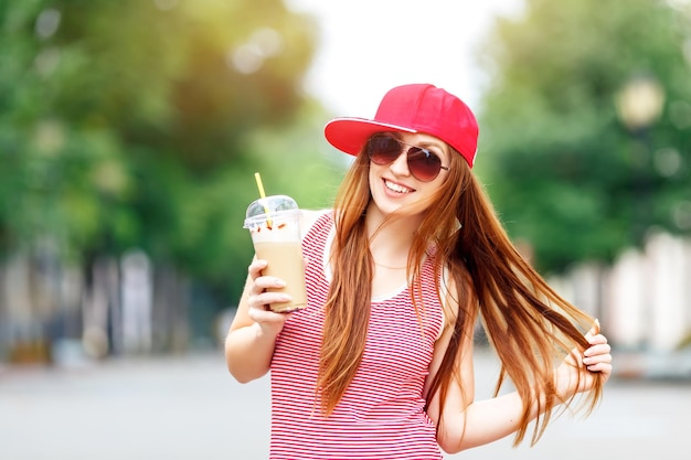 Moda città ritratto di donna alla moda hipster con frappè vestito a strisce rosso berretto rosso e sneaker