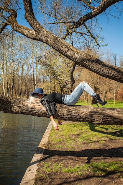 Moda donna sdraiata su un albero nel parco