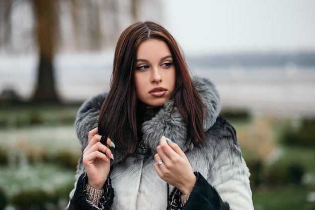 Moda donna sicura di sé in posa fuori strada vestita di pelliccia artificiale in vacanza invernale