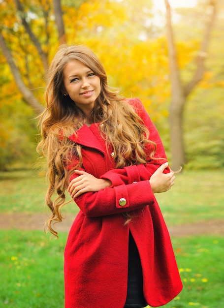 Moda donna vestita di cappotto rosso nel parco d'autunno.