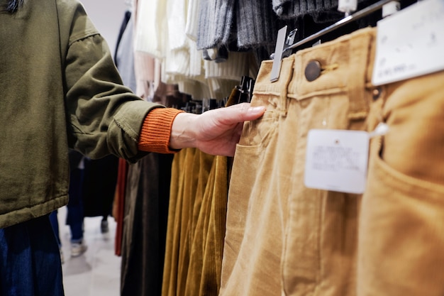 Moda e panno per le donne. Femmina scegliendo Pant in negozio di abbigliamento