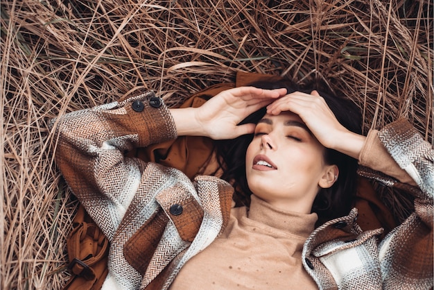 Moda giovane bella donna nel paesaggio autunnale con fiori secchi