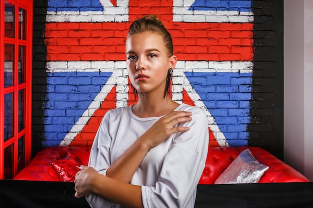 Moda glamour ritratto di una ragazza modello con maglione bianco su sfondo muro con una bandiera britannica