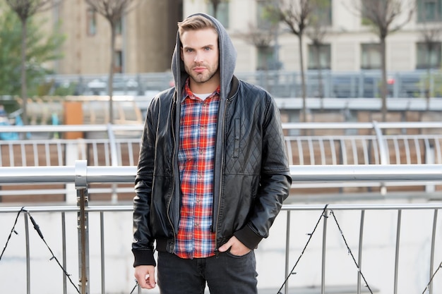 Moda per lo stile di vita urbano. Bel ragazzo indossa una giacca alla moda con cappuccio. Giovane in stile autunnale all'aperto. Guardaroba alla moda per l'autunno. Tendenze moda uomo e stile stagionale.