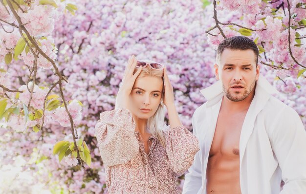 Moda primaverile Ritratto all'aperto di coppia alla moda in posa vicino a fioritura sakura Modello che indossa il porcile