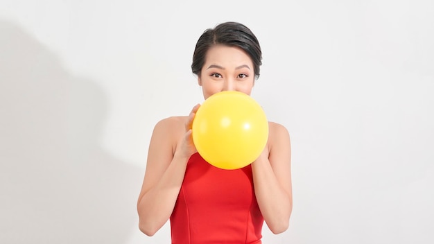 Moda Ragazza di bellezza che soffia un pallone giallo Ritratto splendido della donna Taglio di capelli e trucco alla moda