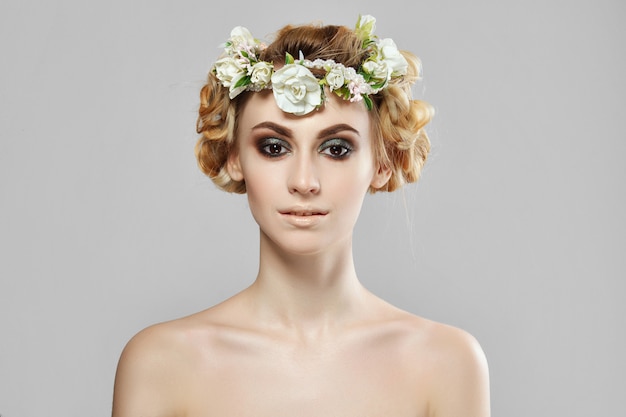 Moda ragazza modello di bellezza con fiori tra i capelli. Trucco creativo perfetto e acconciatura artistica floreale.