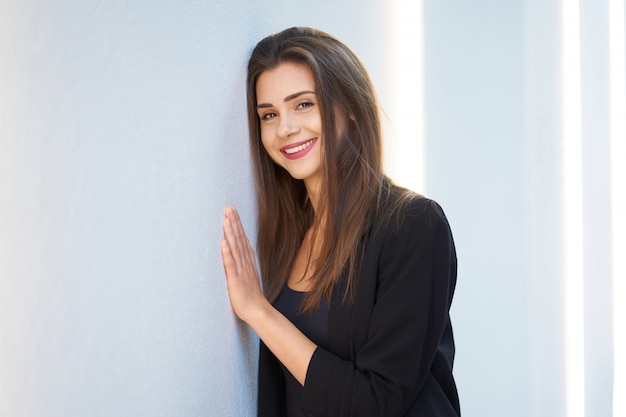 Moda. Ritratto del primo piano di giovane ragazza sveglia felice con il sorriso affascinante che porta giacca nera d'avanguardia