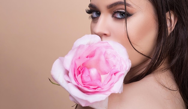 Moda ritratto di giovane bella donna con occhi azzurri e rosa rosa Closeup ritratto di una bella ragazza con una rosa rosa vicino al viso