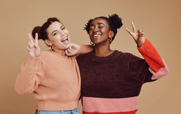 Moda segno di pace e donne amiche in studio con gesto della mano sorriso e felicità su sfondo marrone Libertà bellezza e donna nera con ragazza felice per cosmetici rilassanti ed emoji insieme