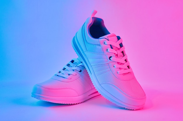 Moda sneakers bianche in luce al neon. Scarpe sportive per l'allenamento in palestra. Minimalismo creativo.