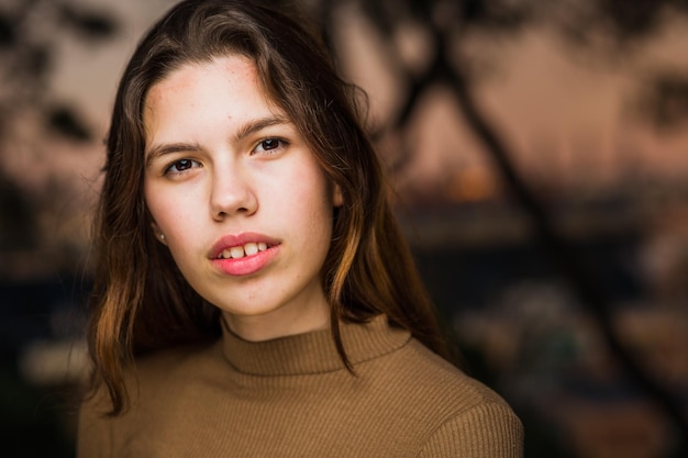 Modella latina giovanile di moda con capelli lunghi in primo piano Faccia carina di scolaressa con abiti marrone chiaro e capelli lunghi