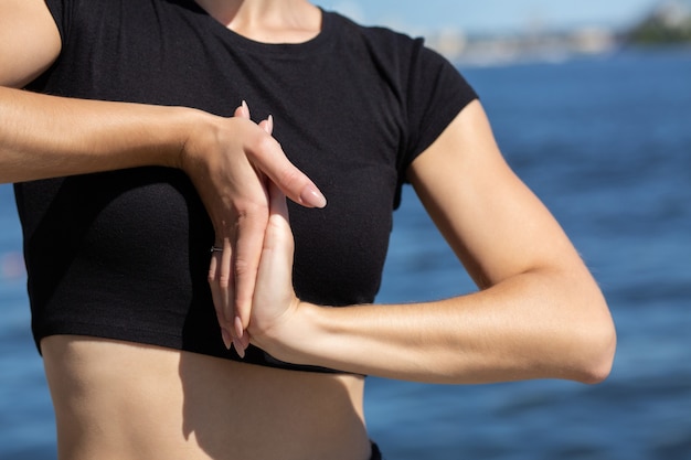 Modello abbronzato snello che indossa una maglietta sportiva che allunga le mani in spiaggia. Spazio per il testo