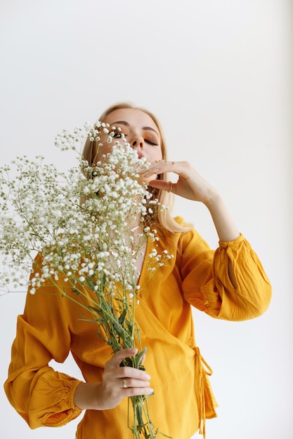 Modello alla moda in una camicetta gialla con fiori bianchi secchi e trucco alla moda