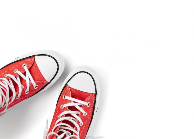 Modello con calzature estive su sfondo bianco. Scarpe da ginnastica rosse piatte con vista dall'alto con spazio di copia. Concetto di vendita dello shopping di moda