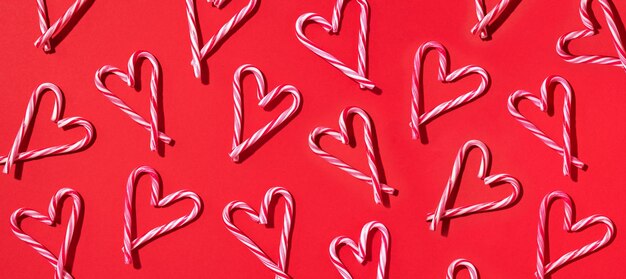 Modello con cuori fatti di bastoncini di zucchero di Natale su sfondo rosso Vista dall'alto Disposizione piatta Amore concetto di San Valentino Nuovo anno e biglietto di Natale Banner
