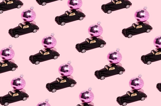 Modello creativo fatto di auto che consegna una palla da discoteca rosa o una pallina di Natale Sfondo rosa pastello