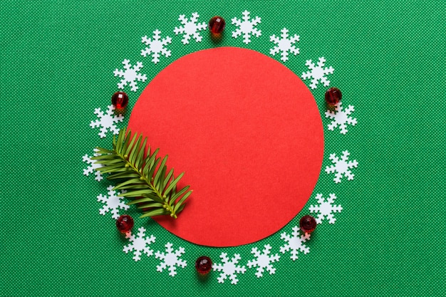 Modello del cerchio di Natale di inverno con le palle rosse dei fiocchi di neve e il cerchio di carta rosso su verde