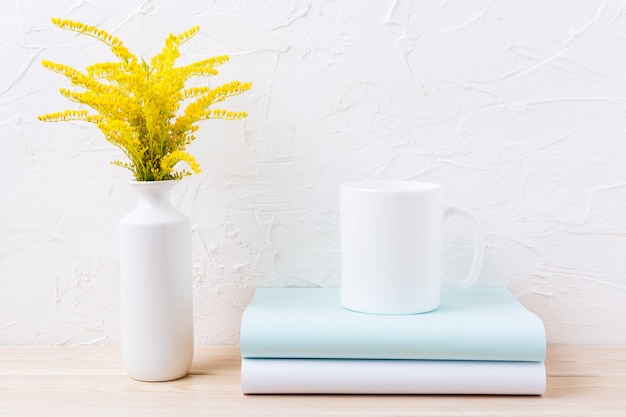 Modello della tazza di caffè bianco con erba di fioritura gialla ornamentale