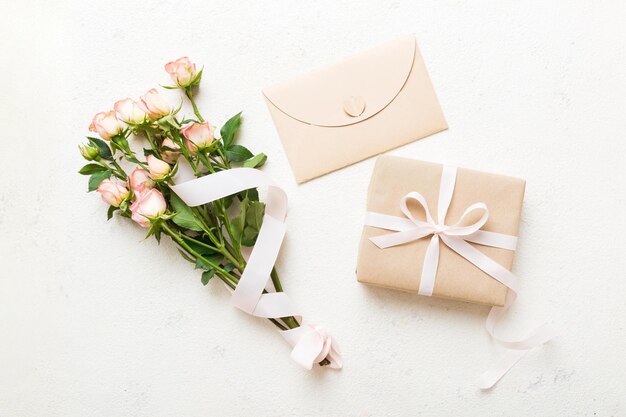 Modello di biglietto di auguri con spazio di copia nastro rosa e rose fiori sullo sfondo colorato del tavolo vista superiore piatta concetto di festa del giorno della madre