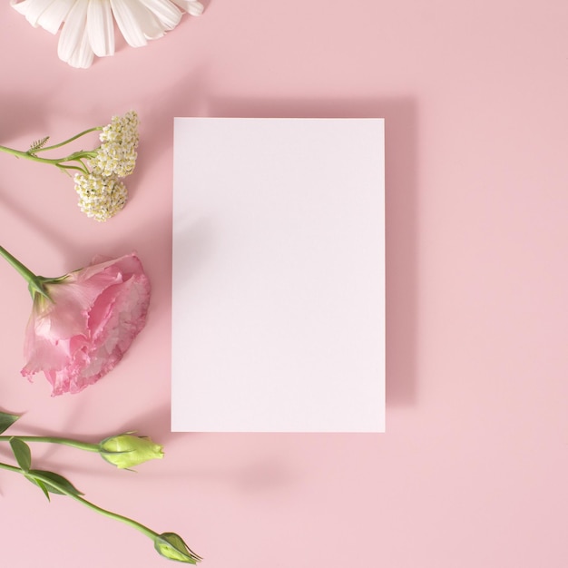 Modello di biglietto di auguri e fiori su sfondo rosa vista dall'alto flatlay Modello di carta con spazio di copia