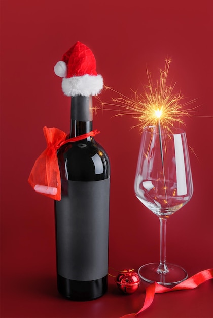 Modello di bottiglia di vino rosso con etichetta nera con Babbo Natale rosso e bicchiere di vino con stelle filanti. Messa a fuoco selettiva. Buon Natale e felice anno nuovo concetto festivo invernale