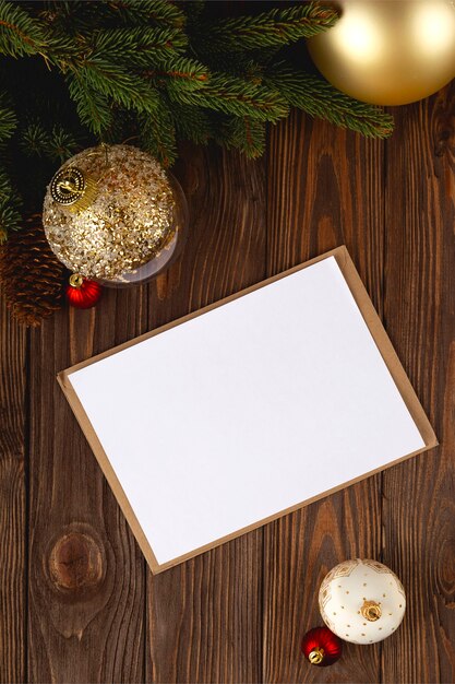 Modello di cartolina di Natale. Cartolina vuota minima bianca sul tavolo di legno con decorazioni festive e busta artigianale.