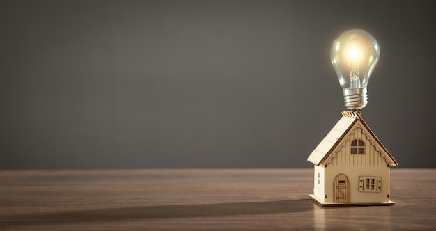 Modello di casa e lampadina sul tavolo di legno