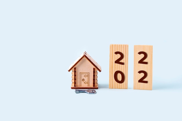 Modello di casa in legno, blocchi con numeri di iscrizione 2022 e chiave. Concetto di acquisto e vendita di case e immobili nel nuovo anno. Assicurazione casa, proprietà e mutuo.