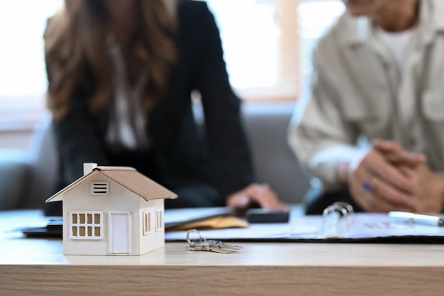 Modello di casa su tavola di legno e consulente finanziario contratto di mutuo ipotecario con uomo anziano in background