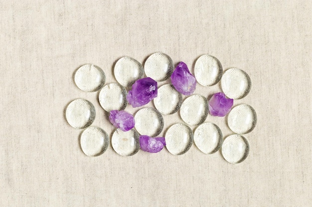 Modello di cristalli di ametista viola e pietra rotonda di vetro su sfondo tessile vista dall'alto naturale