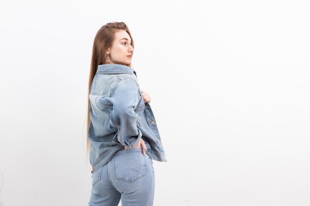 Modello di donna alla moda sexy moda vestita di jeans e giacca di jeans su priorità bassa bianca