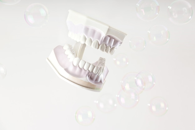Modello di ganasce con denti bianchi tra bolle di sapone su sfondo chiaro