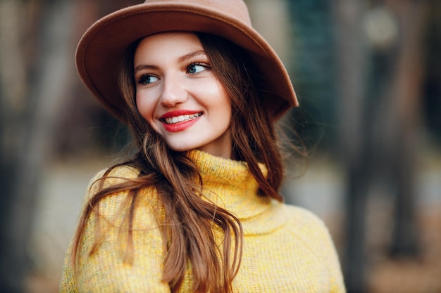 Modello di giovane donna nel parco autunnale con foglie di acero fogliame giallo Moda autunnale