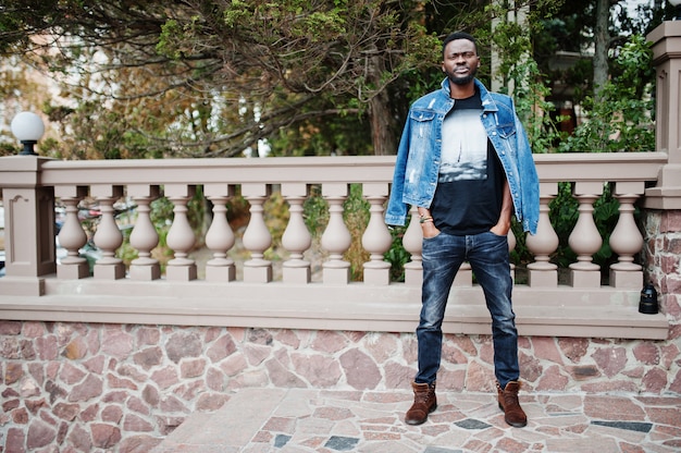 Modello di giovane uomo afroamericano serio attraente. Tirante bello moderno in rivestimento dei jeans che sta sulla via urbana della città.