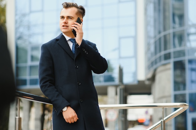 Modello di giovane uomo d'affari bello fiducioso elegante in abiti vestito che cammina per la strada.