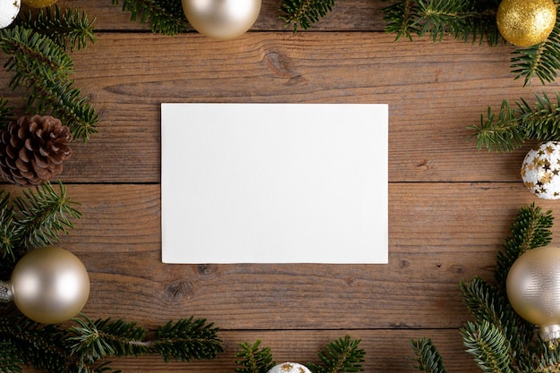 Modello di mockup di carta di Natale 7x5 su ramoscelli di abete naturale su fondo in legno Elemento di design per Natale e Capodanno