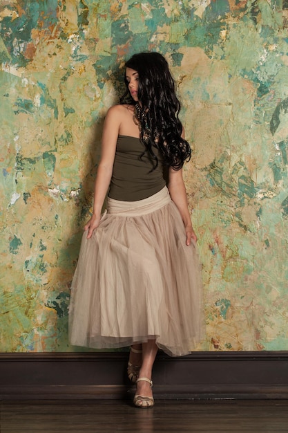Modello di moda della bella giovane donna castana sui cenni storici della parete verde