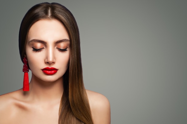 Modello di moda donna con trucco labbra rosse e orecchini gioielli setosi su sfondo con spazio copia